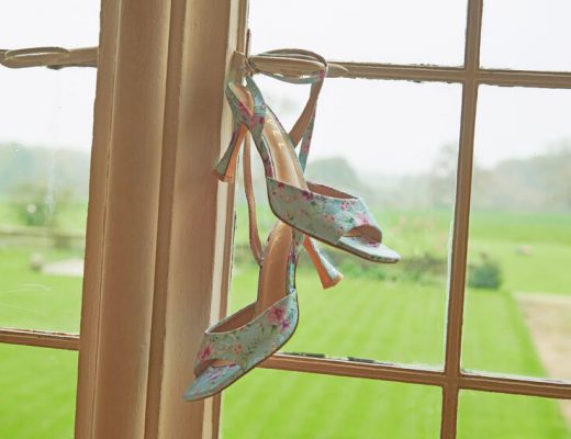 Blue floral shoes hanging from a window pane